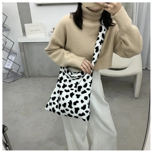 Detailed view of plush cow print crossbody bag worn with a beige autumn sweater