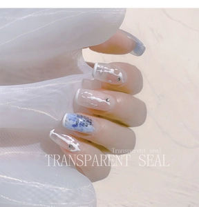 Close-up of blue marble ombre press-on nails with 3D line art and sparkling rhinestones