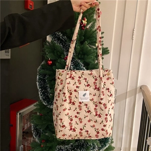 Detail of beige corduroy tote bag with red floral print and metal snap button closure