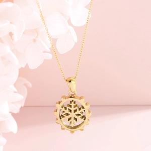 Golden snowflake pendant necklace set with gear frame on a soft pink background