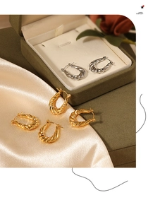 Detailed macro shot of vintage twisted texture hoop earrings in gold and silver finish