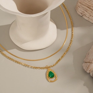 Elegant gold double layer necklace with green teardrop pendant on minimalist background