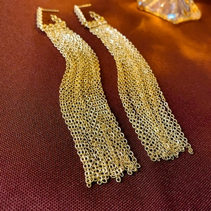 Detail of gold long chain tassel earrings with multi-layered fringe and metallic shine