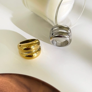 Detailed view of chunky irregular wave rings in polished gold and silver finishes
