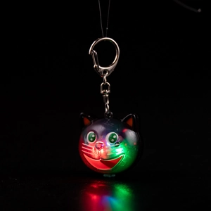 Close-up of glowing cat-shaped LED keychain with vibrant red and green light effects