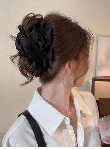 Detailed view of the black pleated fabric flower hair clip on an elegant updo hairstyle