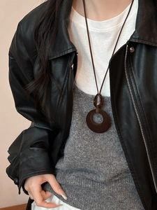 Close-up of a vintage flocked resin pendant necklace worn with a black leather jacket