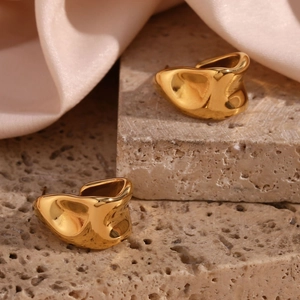 Detailed view of golden irregular geometric earrings on pink silk and marble base