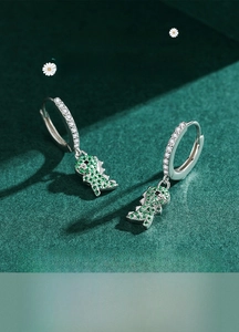 Macro shot of 925 sterling silver dinosaur earrings with green and white cubic zirconia