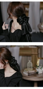 Detailed view of oversized black satin bow scrunchie with elegant long ribbons