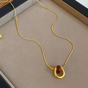 Gold plated U-shape necklace with red gemstone pendant on a flat snake chain