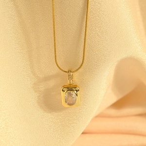 Detailed macro view of an elegant gold square pendant with central oval emerald-cut zircon