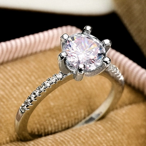 Classic six-prong solitaire ring with pave diamond band on a velvet jewelry box