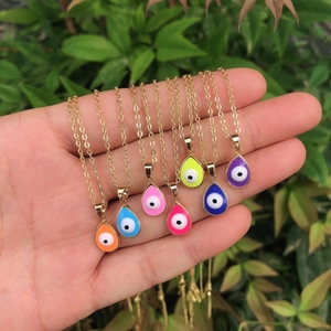 Macro view of multi-color teardrop evil eye pendants on gold-plated necklaces