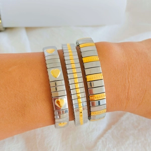 Close-up of three-piece modular stretch bracelets with heart motif and mixed-metal finish