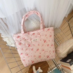 Detail of pink floral quilted cotton handbag with simple wish label on metal rack