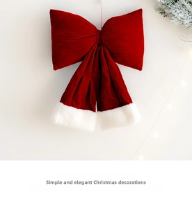 Detail of red velvet Christmas bow with white faux fur trim and festive warm lighting