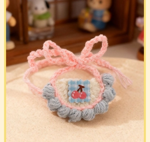 Close-up of handmade crochet pet collar with cherry embroidery and gray pom-pom trim
