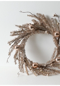 Detail of a champagne gold Christmas wreath with metallic ornaments on a white background