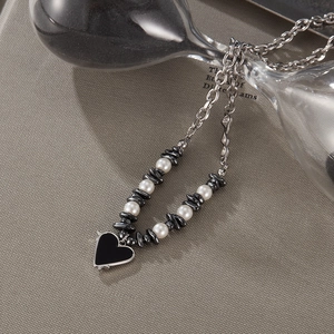 Macro view of titanium steel necklace featuring black heart pendant and white pearls