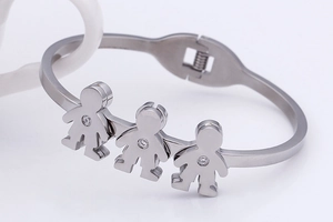 Macro detail of silver bangle featuring three abstract figures with zircon accents