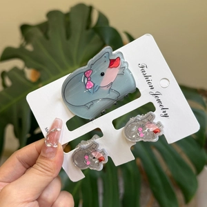 Detailed view of three gray acrylic mouse hair clips with pink bows on a display card
