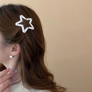 Detail of white star hair clip with black dot stitching on brunette hair for stylish look