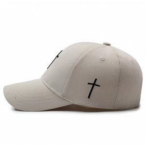 Beige cotton baseball cap with black cross embroidery and curved brim in side view