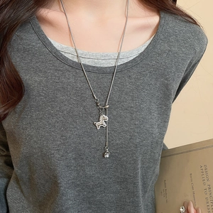 Close-up of zircon pony pendant necklace on a grey sweater with silver snake chain detail