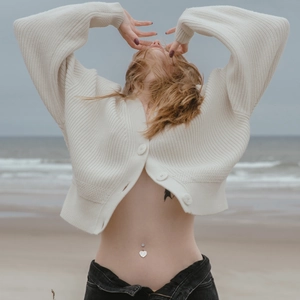 Macro shot of butterfly zircon belly button ring worn on body with beach backdrop