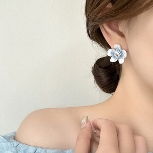 French vintage flower stud earrings with blue petals and crystal center on ear model