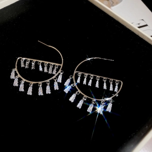 Close-up of sparkling zircon drop earrings with shimmering light effect on black velvet