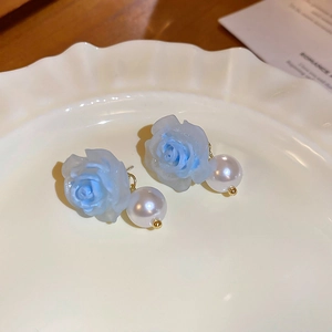 Macro de boucles d'oreilles roses bleues et perles sur un plateau à bijoux en céramique