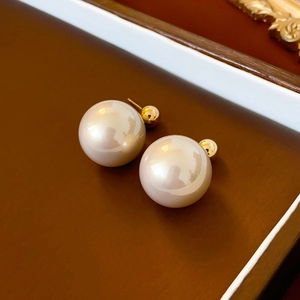Macro detail of elegant double pearl gold earrings on a minimalist brown wooden tray