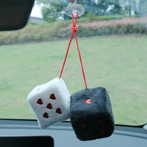 Detail of plush black and white car dice with red heart dots hanging on rearview mirror