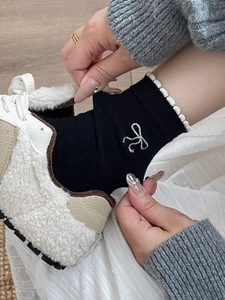 Detail von schwarzen Socken mit silberner Schleifenstickerei und weißem Rüschenrand