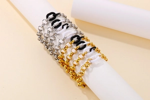 Détail d'un bracelet à grosse chaîne avec maillons or et argent et breloques résine