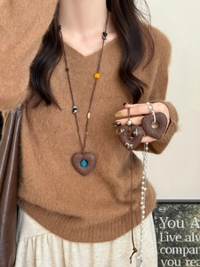 Detail of brown heart pendant with matte texture and blue bead on long beaded necklace