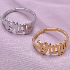 Detail of adjustable gold and silver rings with gothic Baby lettering on lilac fabric