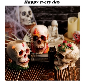 Detailed resin skull ornaments with mushroom, flame, and rose floral motifs on a desk