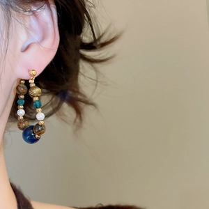 Detail of drop pearl earrings with tiger eye and blue beads on female model