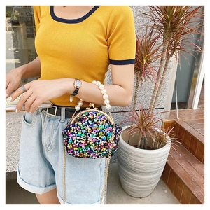 Detail of colorful sequin evening bag with pearl handle and golden chain strap
