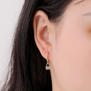 Gros plan de créoles cadenas dorées avec pavé de diamants portées par un mannequin