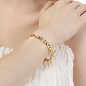 Gros plan d'un bracelet en acier titane doré avec cristaux ronds sertis en chaton