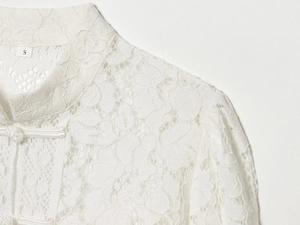 Close-up of white lace shirt detailing Chinese mandarin collar and traditional frog button