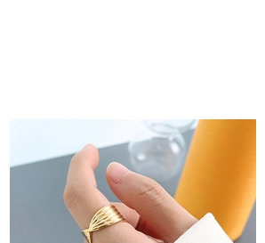 Close-up of golden wide twisted wave ring worn on finger for a stylish minimalist look