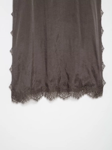 Close-up of silk fabric hem with delicate lace trim on a dark brown lace lingerie camisole