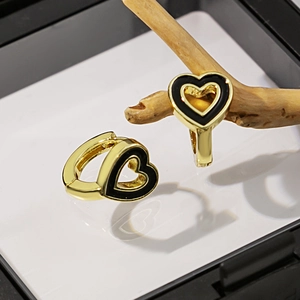 Détail de boucles d'oreilles cœur dorées avec émail noir et projection d'ombre unique