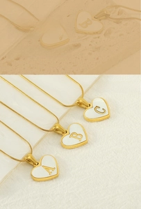Detailed view of three 18K gold plated heart pendants with shell inlay and ABC letters