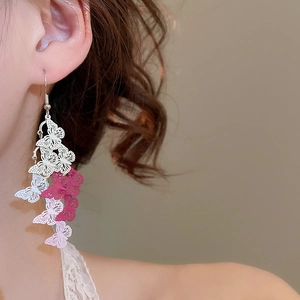 Detail of pink and white gradient hollow butterfly tassel earrings on a model's ear